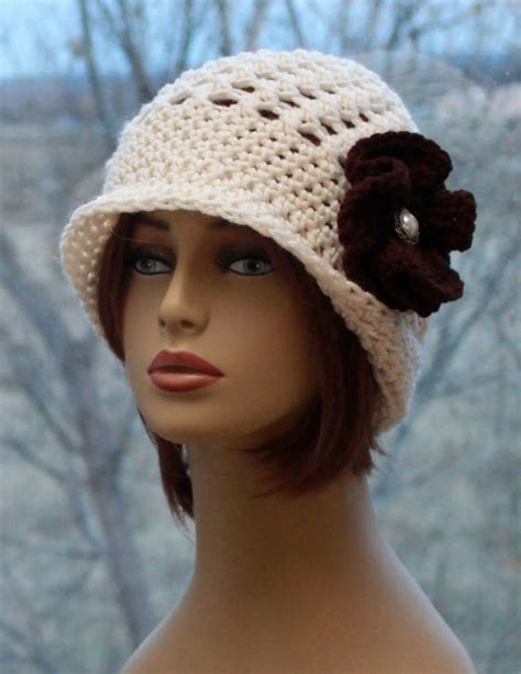 A Mannequin Head Wearing A White Crochet Hat With Brown Flowers On It