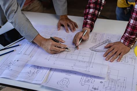 Engineer Pointing At Blueprint And Using Laptop To Draw Project Design