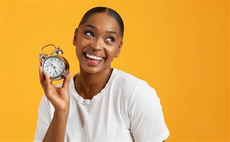 Premium Photo Cheerful Black Millennial Woman Holding Alarm Clock On