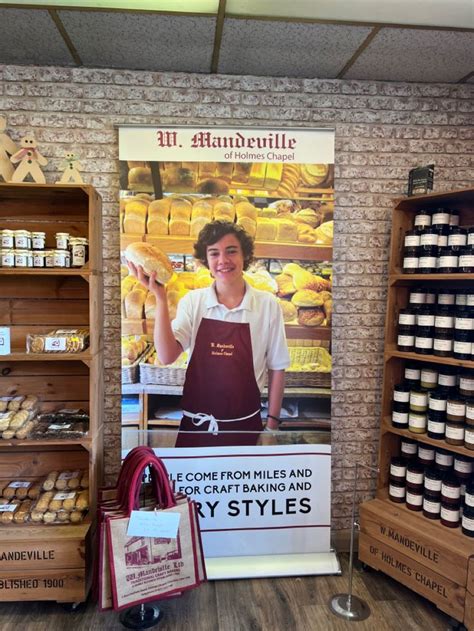 A Man Standing In Front Of A Display Of Baked Goods At A Bakery With An