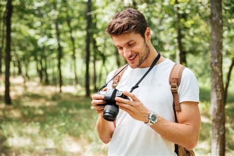 Smiling Man Photographer Using Modern Photo Camera In Forest Stock