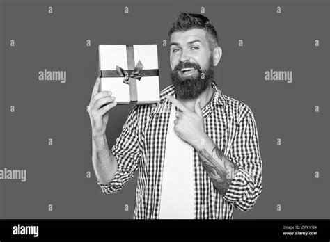 Mature Bearded Guy With Present Box On Grey Background Pointing Finger
