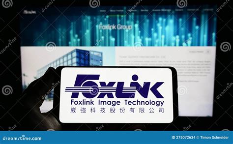 Person Holding Smartphone With Logo Of Company Foxlink Image Technology