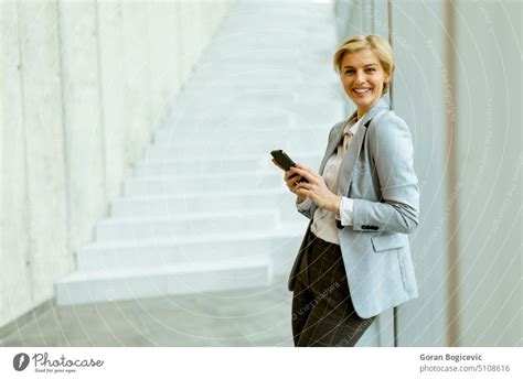 Business Woman Using Cell Phone In A Modern Office Hallway A Royalty