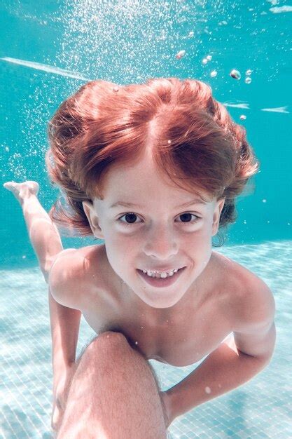 Niño sonriente nadando bajo el agua en la piscina Foto Premium