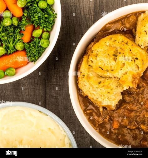 Traditional British Beef Casserole With Dumplings And Mashed Potatoes And Vegetables On A Dark