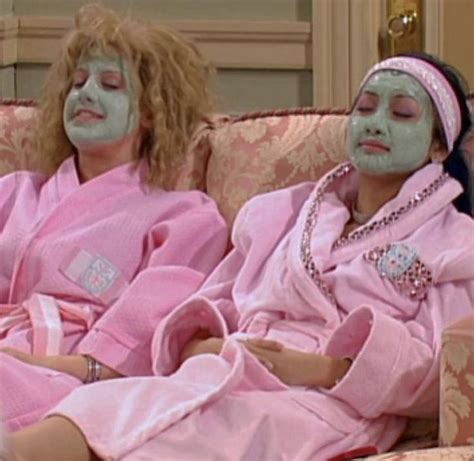 Two Women In Pink Robes Sitting On A Couch With Their Faces Painted