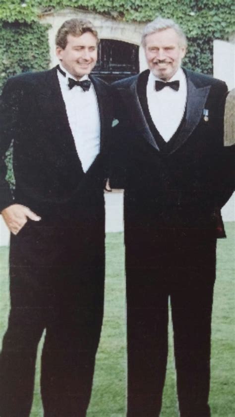 Two Men In Tuxedos Standing Next To Each Other