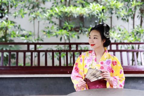 Traditional Asian Japanese Beautiful Geisha Woman Bride Wears Kimono Hold A Fan Reading Book In