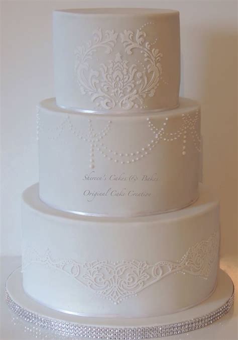 A Three Tiered Wedding Cake With White Frosting And Embellishments On