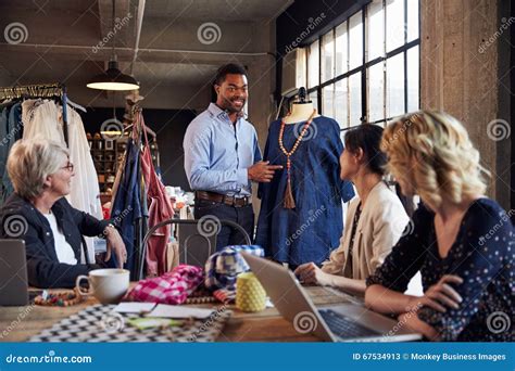 Four Fashion Designers In Meeting Discussing Garment Stock Image