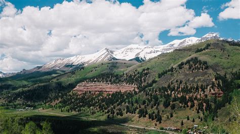 A Valley In Telluride Surrounded By A Hill Covered With Trees And A