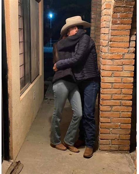 A Man And Woman Standing In Front Of A Brick Building With Their Arms