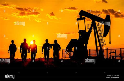 Silhouette Of A Oilfield Worker Crude Oil Pump At Sunset Stock Photo