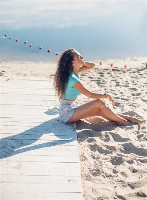 Muchacha Rizada Hermosa Que Se Sienta En La Playa Retrato De La Vista