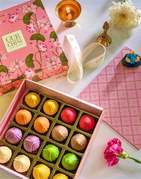 A Pink Box Filled With Assorted Chocolates On Top Of A Table Next To