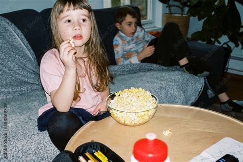 little girl eating popcorn at home in living room Stock Photo | Adobe Stock