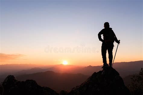 Silhouette Of Hiker Standing On Top Of Hill And Enjoying Sunrise Over