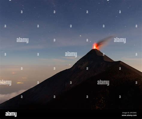 Volcano fuego lava eruption at night with visible stars and city lights ...