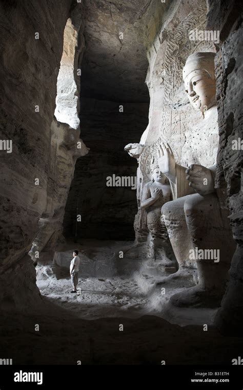 A Man In The Shadows Of A Giant Statue At The Yungang Buddhist Caves