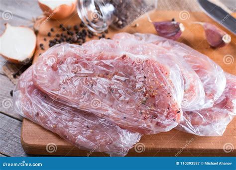 Fresh Raw Pork Chops Meat In A Bag On Chopping Board On Wooden Desk