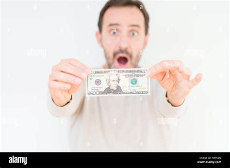Senior man holding twenty dollars bank note over isolated background ...