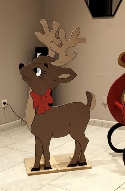 Two Cardboard Reindeers Standing Next To Each Other In A Room With Tile