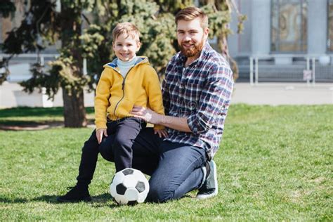 Pai Novo E Seu Filho Que Jogam O Futebol Em Um Parque Imagem De Stock