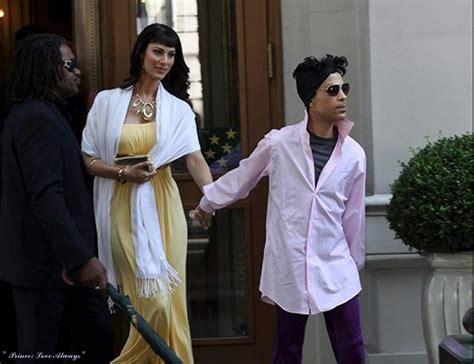 a man and woman holding hands in front of a building with other people ...