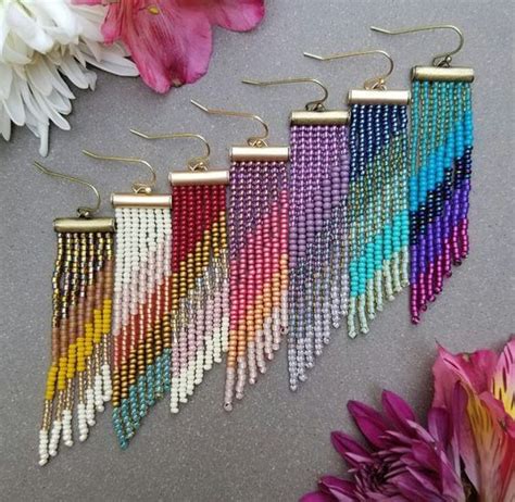 Five Different Colors Of Beads Hanging From Hooks On A Table Next To