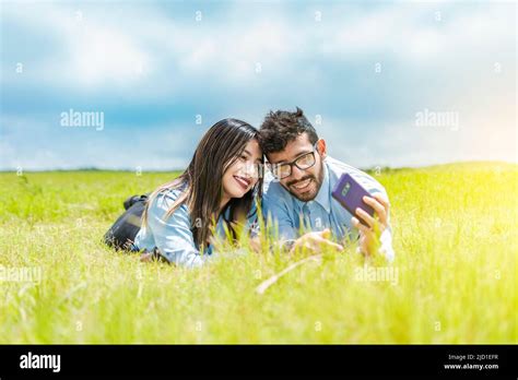 A Couple Lying On The Grass Taking A Selfie Young Couple In Love Lying