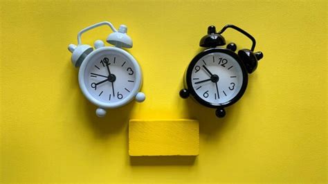 Premium Photo White And Black Alarm Clock On Yellow Background With