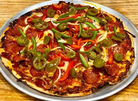 A Pizza Sitting On Top Of A Metal Pan Covered In Toppings And Sauce