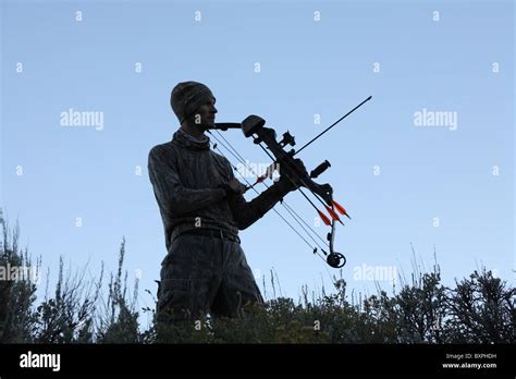 Partial Silhouette Of Bow Hunter Holding Bow And Arrow At Dusk Stock