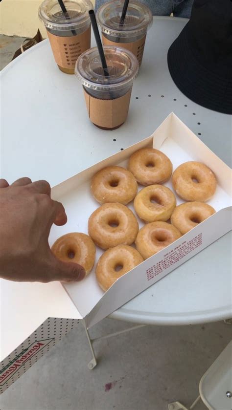 A Box Of Doughnuts Sitting On Top Of A Table Next To Two Cups Of Coffee