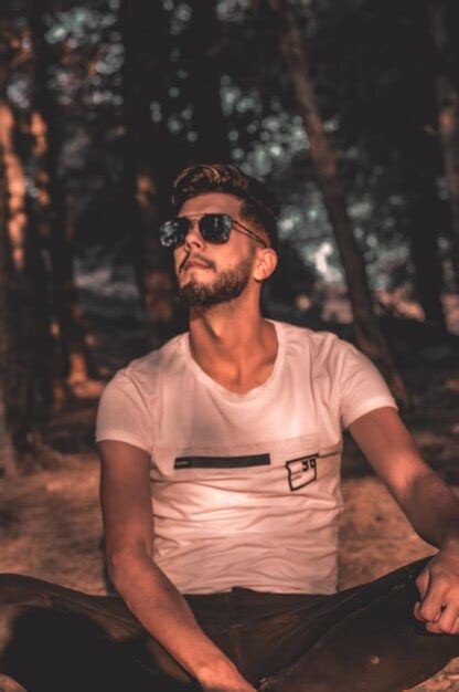 Premium Photo Young Man Wearing Sunglasses Standing Against Trees