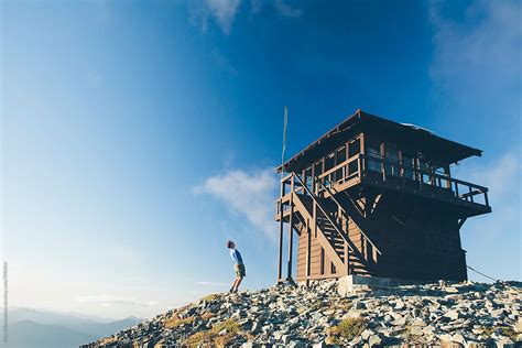 Man Standing Next To Fire Lookout On Mountain Summit Dusk By Stocksy