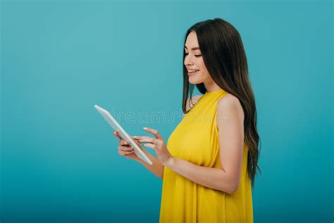 View Of Smiling Girl In Yellow Dress Using Digital Tablet On Turquoise