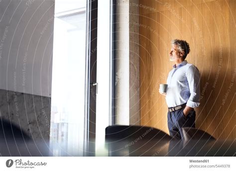 Portrait Of Confident Mature Businessman Loooking Out Of Window A