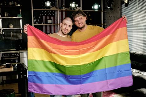 Premium Photo Young Affectionate Homosexual Couple Holding Rainbow Flag