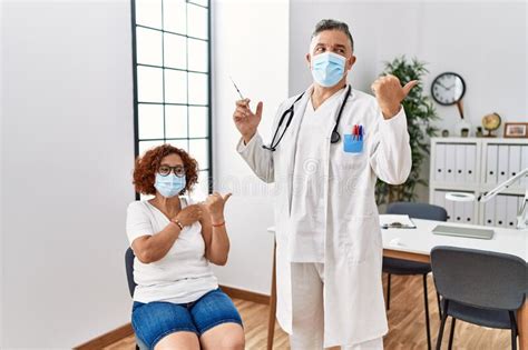 Middle Age Woman Getting Vaccine By Doctor Pointing Thumb Up To The