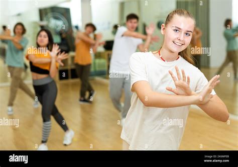 Cheerful teen girl training movements of group dance in choreography ...