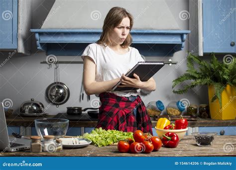 Young Girl Prepares A Vegetarian Salad In The Kitchen And Looks Into A