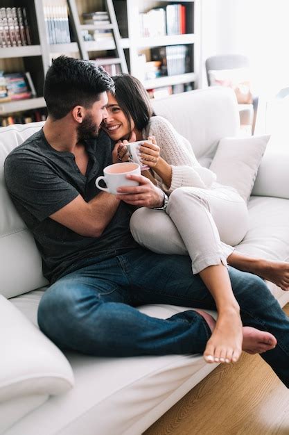 Free Photo Romantic Couple Sitting On Sofa Holding Coffee Cup Looking At Each Other