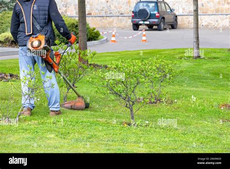 Un Jardinier Avec Un Coupe Herbe S Occupe Soigneusement De La Pelouse