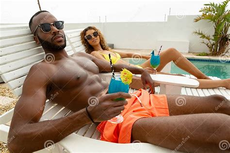 Couple Having Cocktail Drink While Relaxing On A Sun Lounger Stock