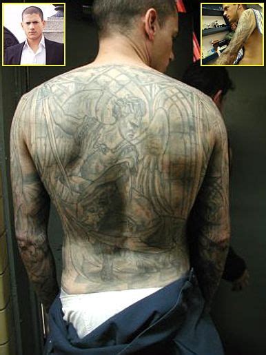 a man with tattoos on his back standing in front of a mirror