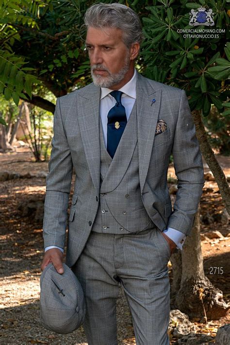 A Man In A Suit And Tie Is Holding A Hat While Standing Under A Tree