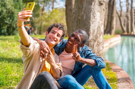 Selfie de um casal gay multiétnico falando baixinho no conceito lgbt do parque Foto Premium