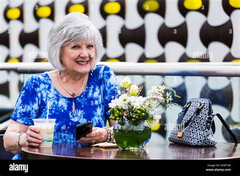 Mature Woman Checking Her Cell Phone For Messages While Drinking An Iced Coffee At A Cafe St